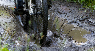 Mountain bike ride through a deep puddle on a muddy trail